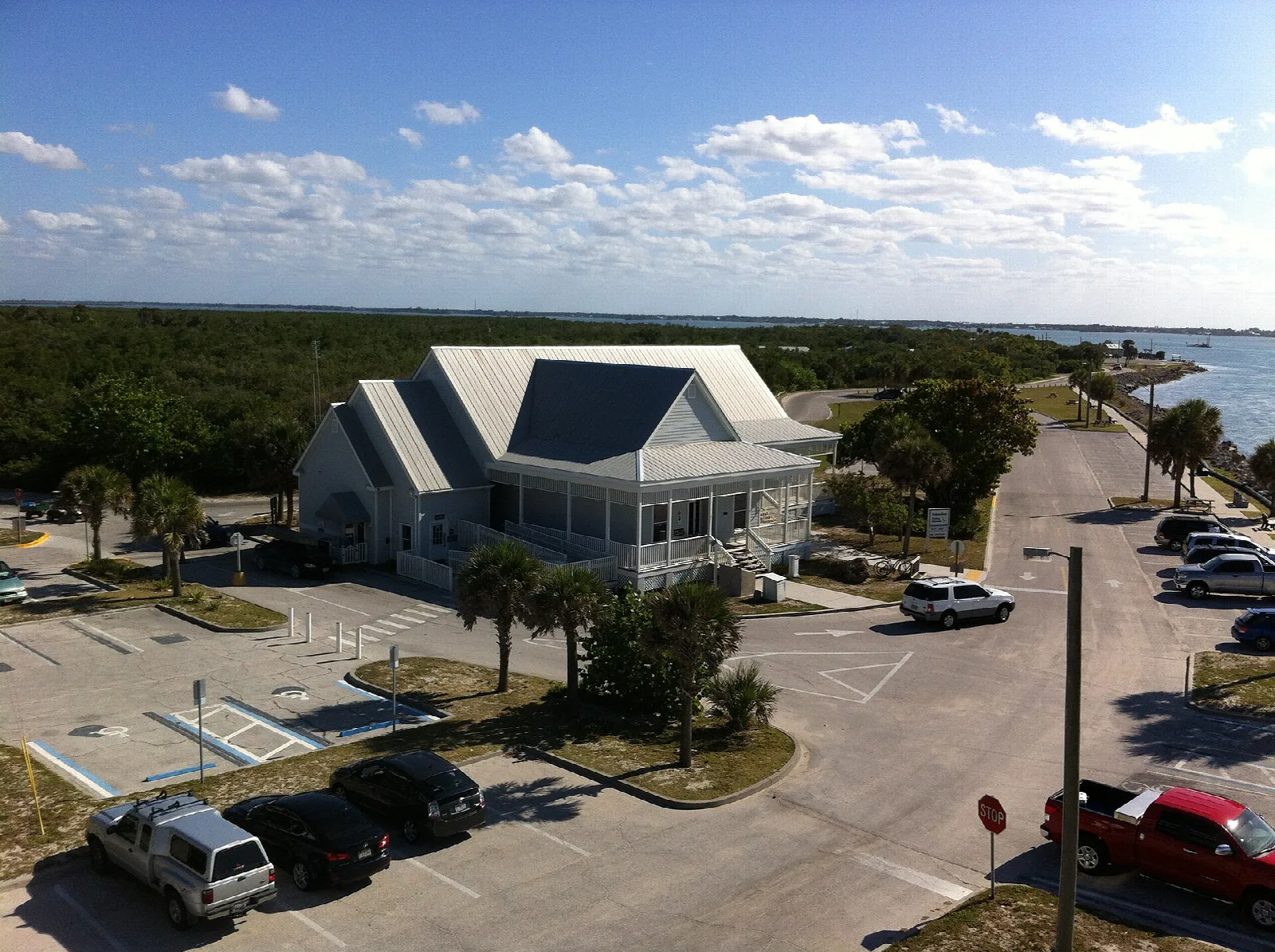 Light building with a gabled roof and parking beside the water