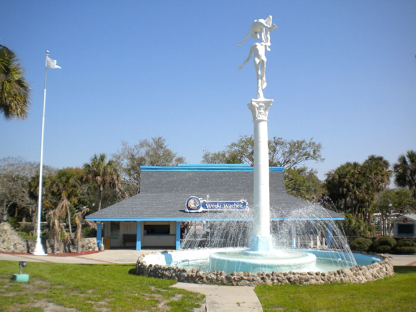 Blue-roofed building behind a white fountain column and lawn