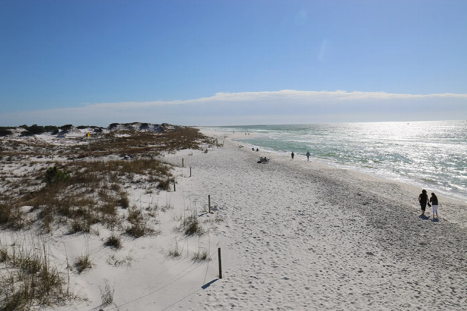 White sand beach and dunes with two walkers beside Gulf water