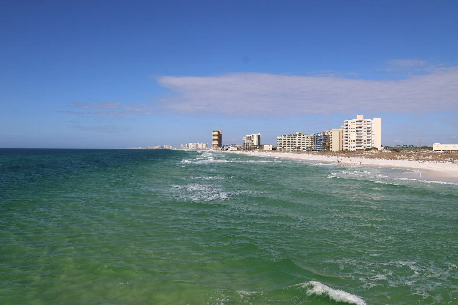 Green surf along a beach with high-rise condos far off
