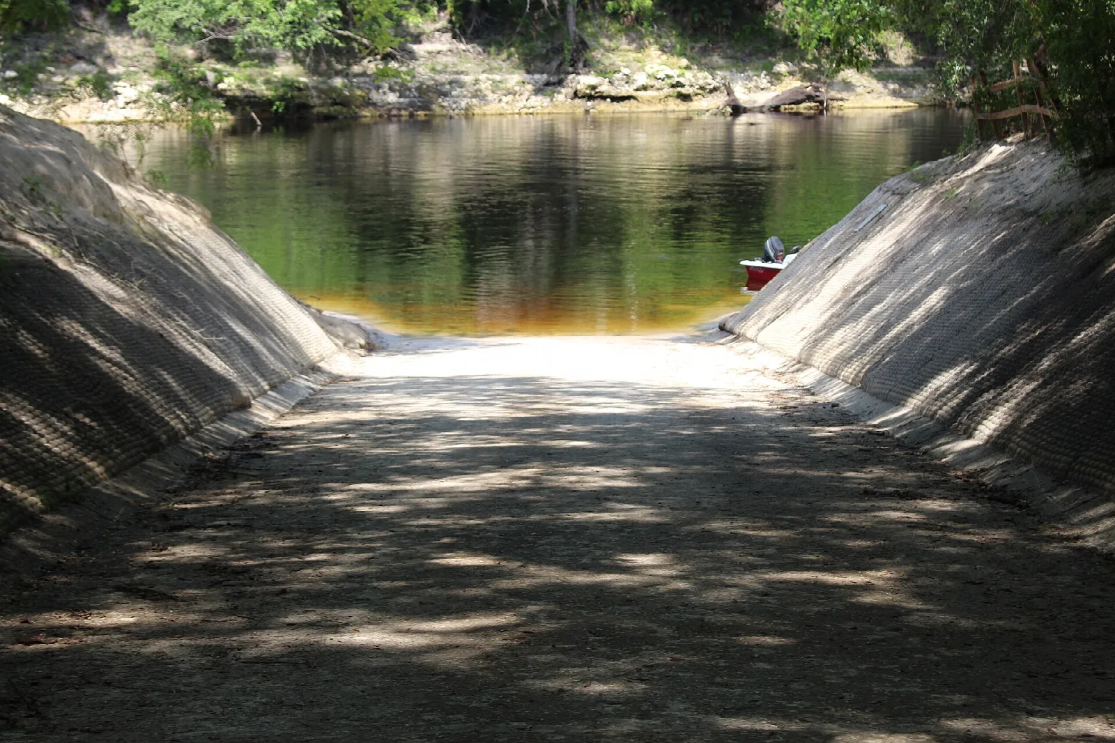 Concrete boat ramp sloping down to dark river water