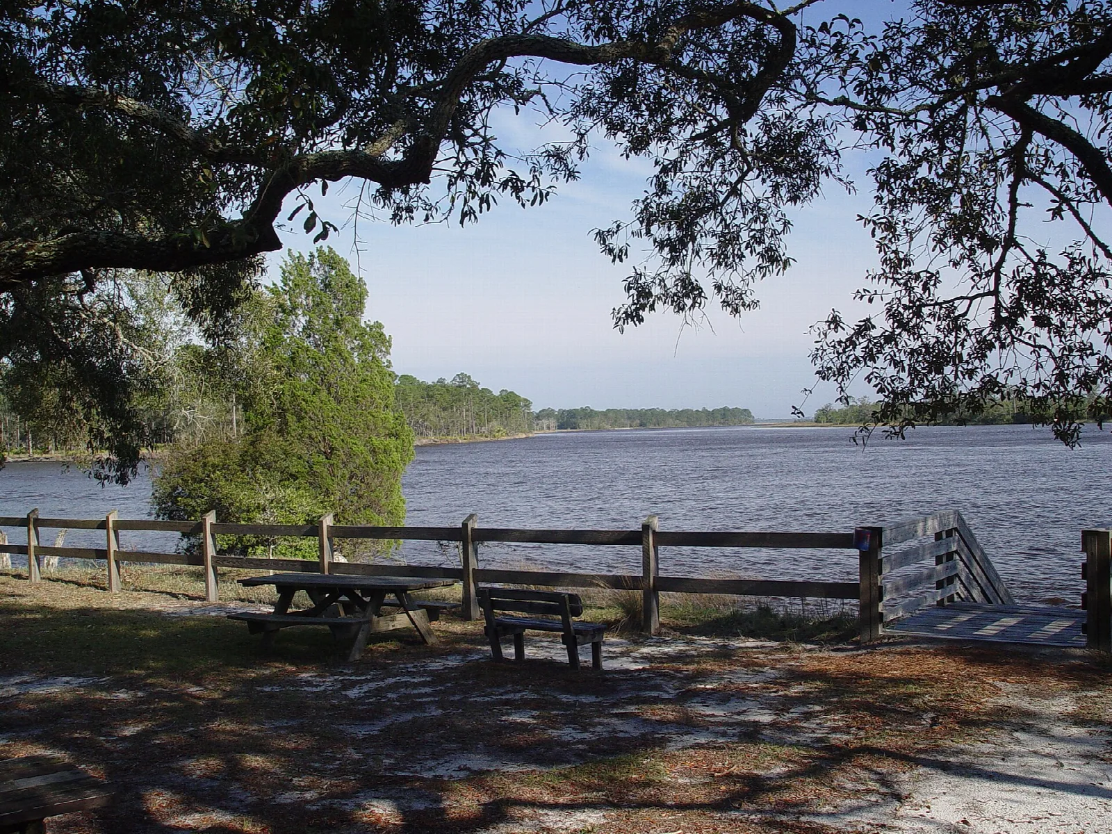 Picnic table and fence at the edge of a blue lake
