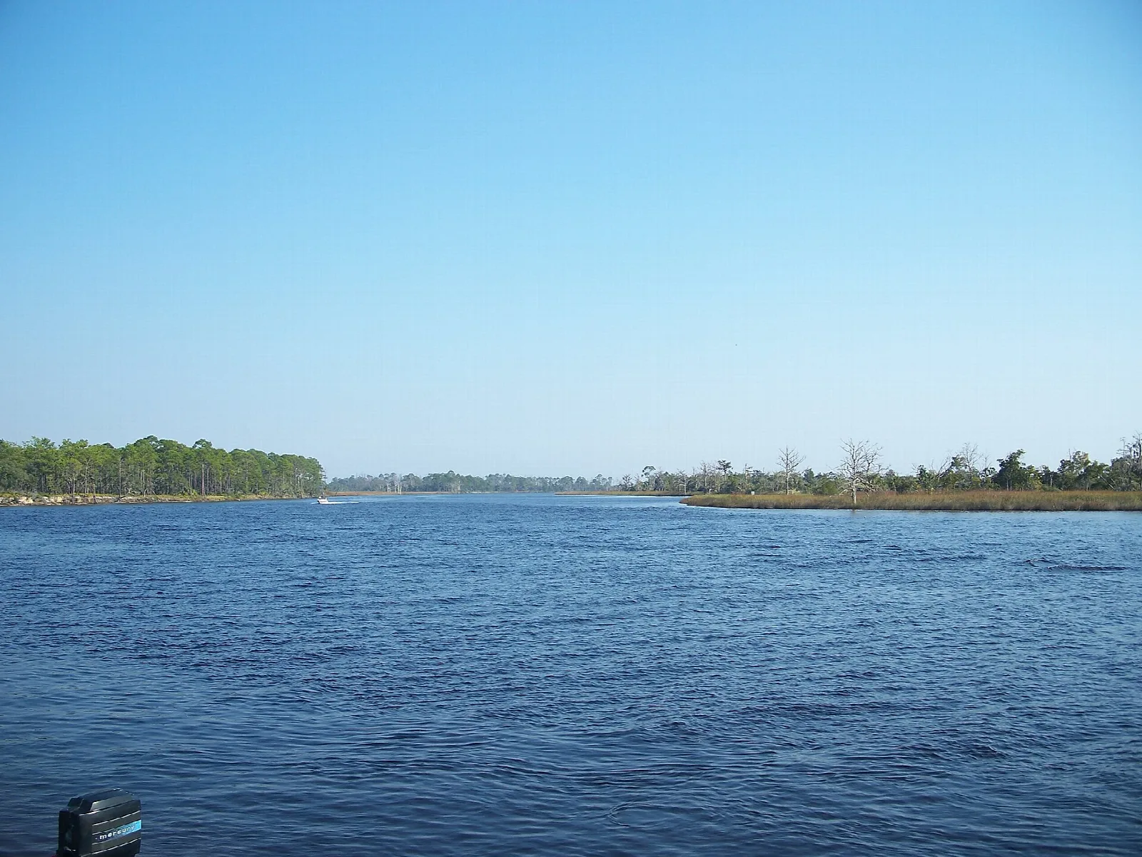 Wide blue river with low marsh banks under clear sky