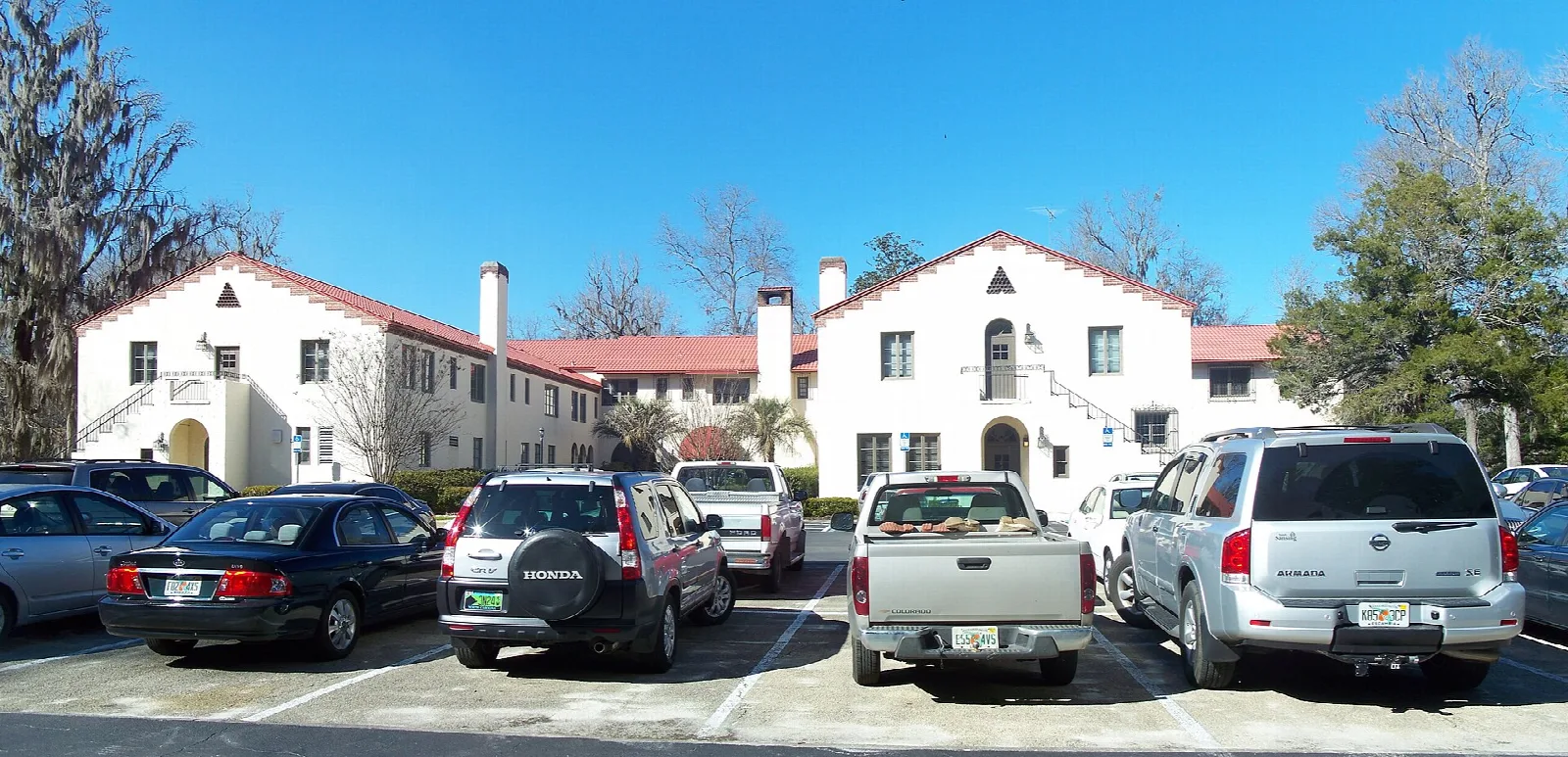 White Spanish-style lodge with red roof and parked cars
