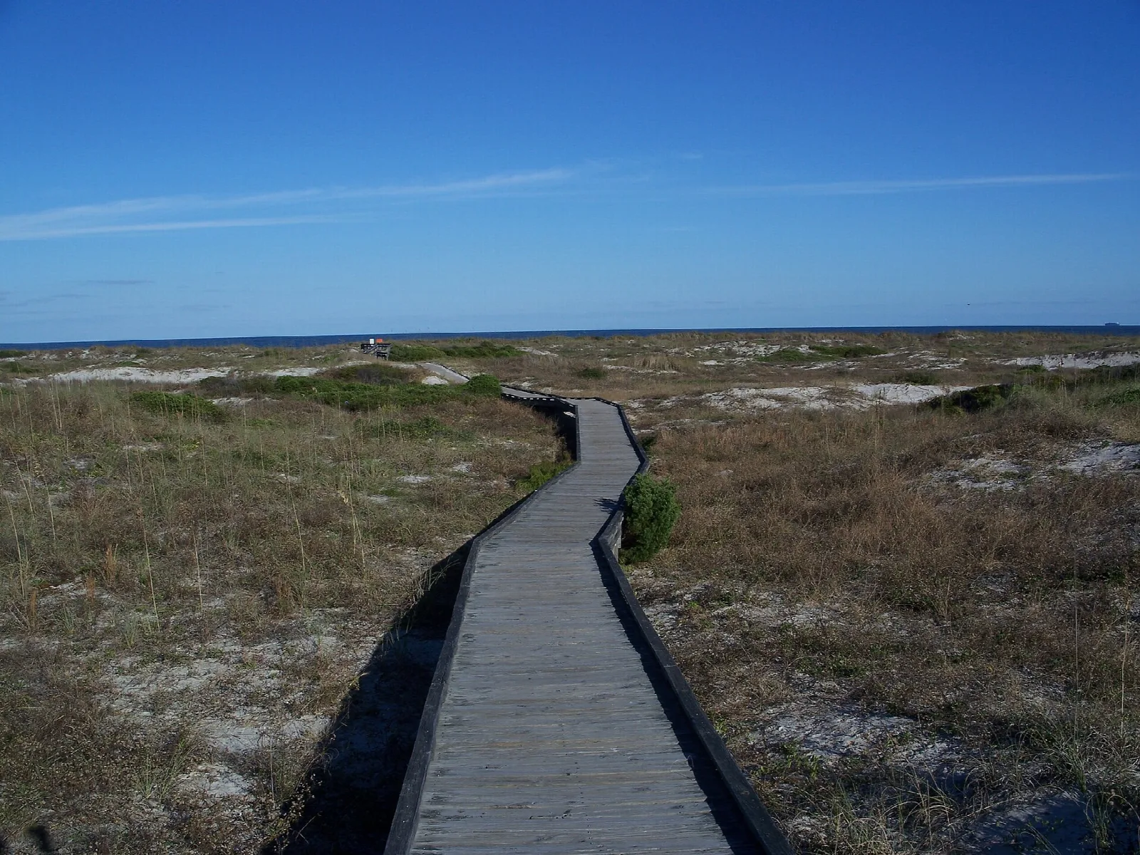 Narrow boardwalk winding across dunes