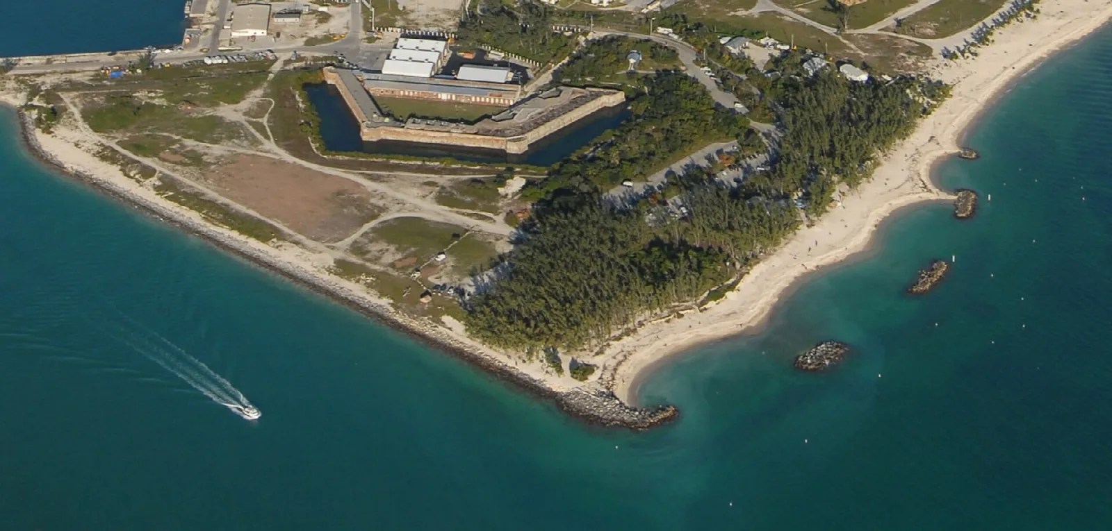Aerial view of a square brick fort on a point surrounded by beach and turquoise water