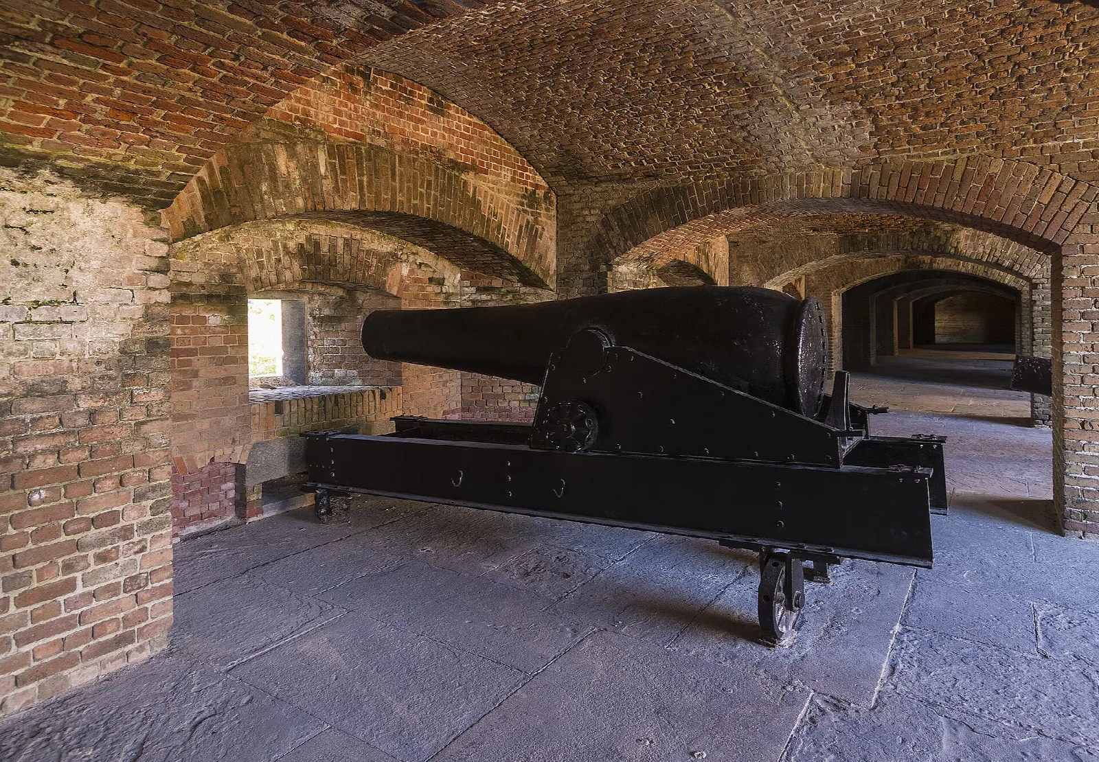 Old black cannon inside a brick casemate with arches