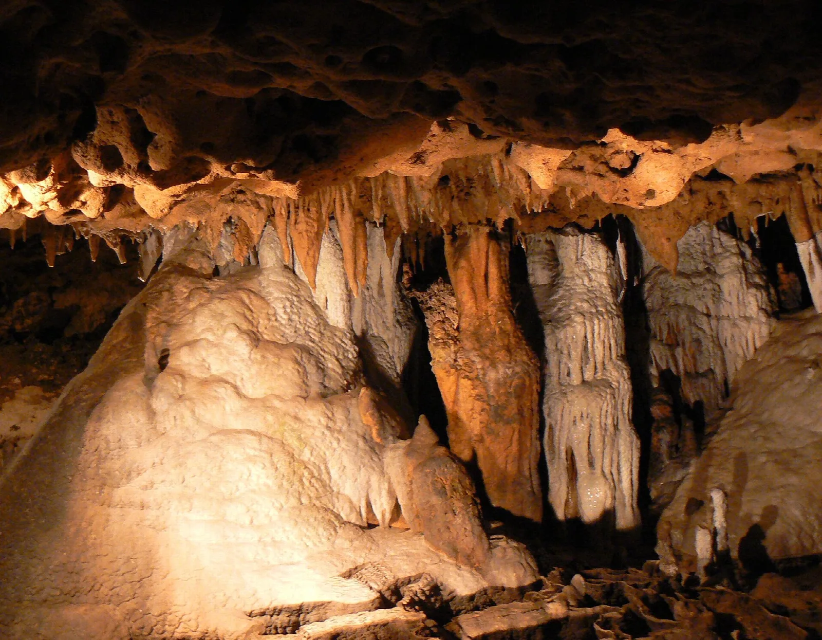Lit cave with pale stalactites and flowstone