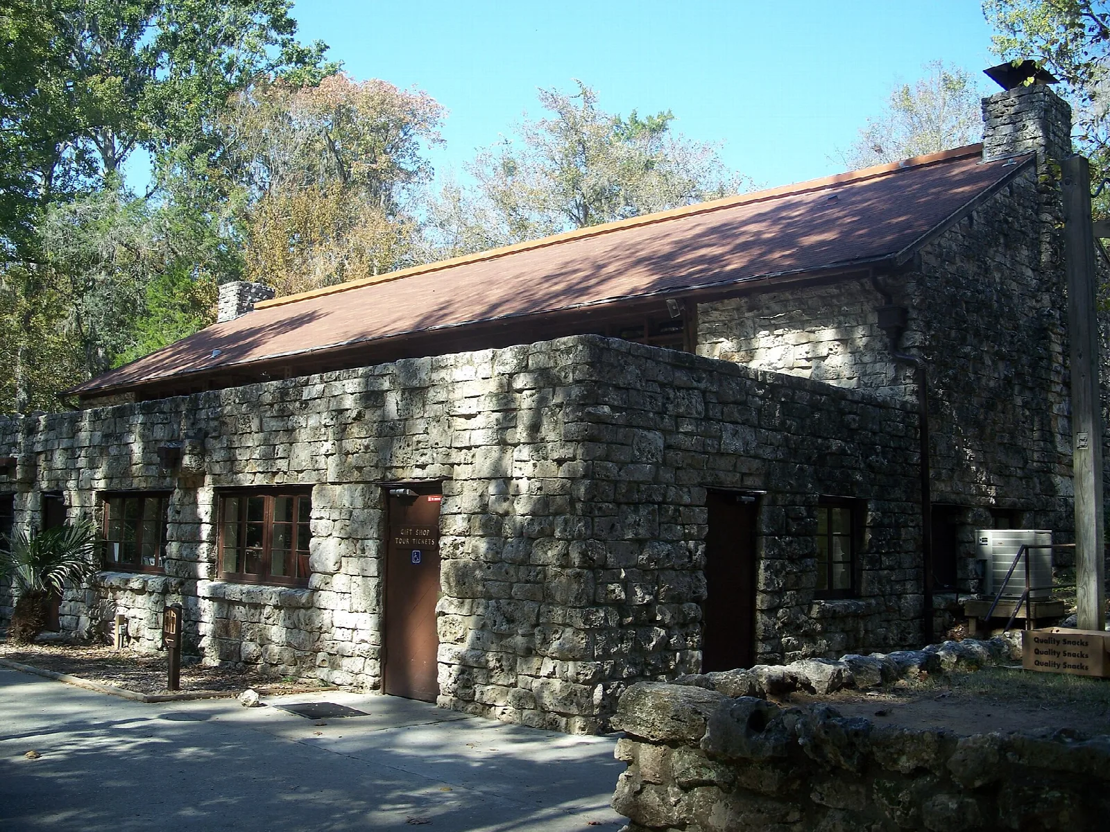 Stone building with a red roof beside a parking area