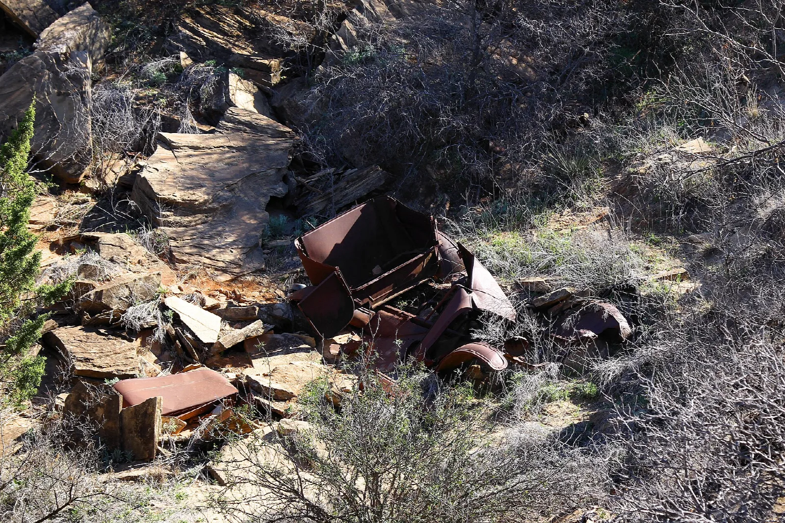 Rusted wreck of an old car in a rocky ravine