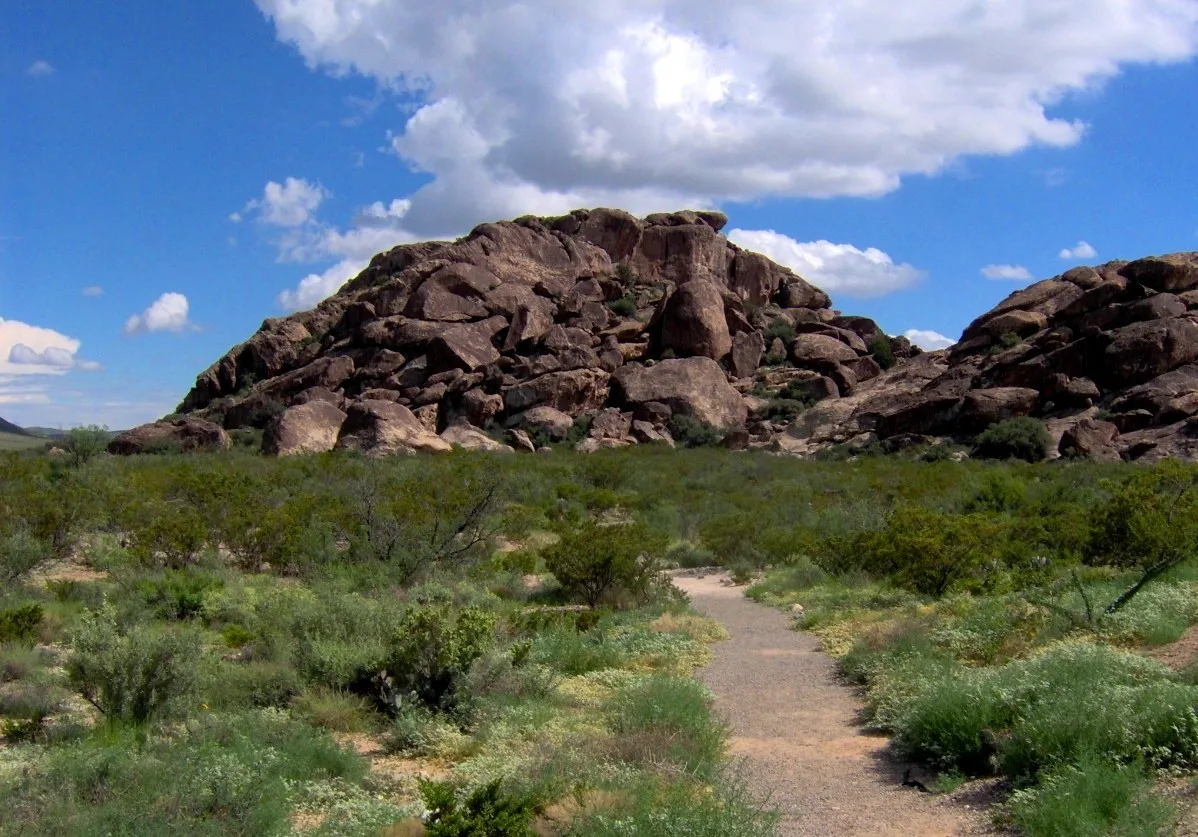Dark rock hills rising above desert brush with a dirt path