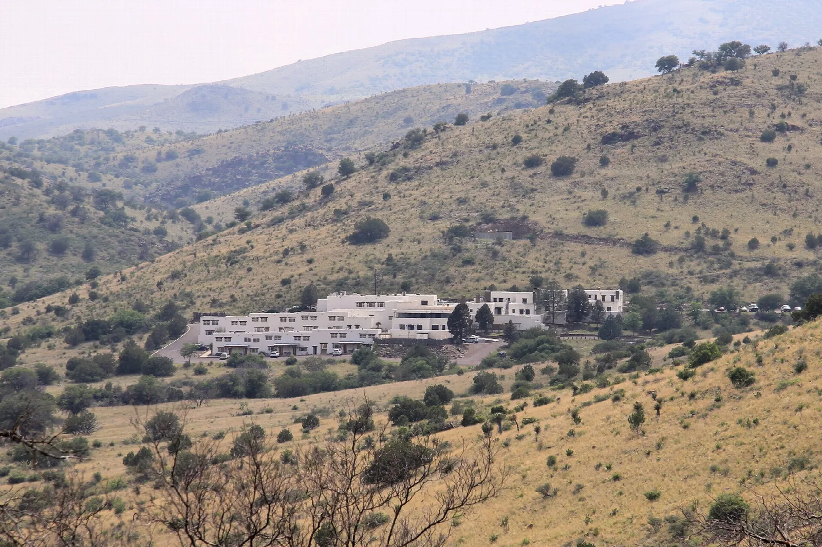 Long white lodge building on a hillside with mountains behind