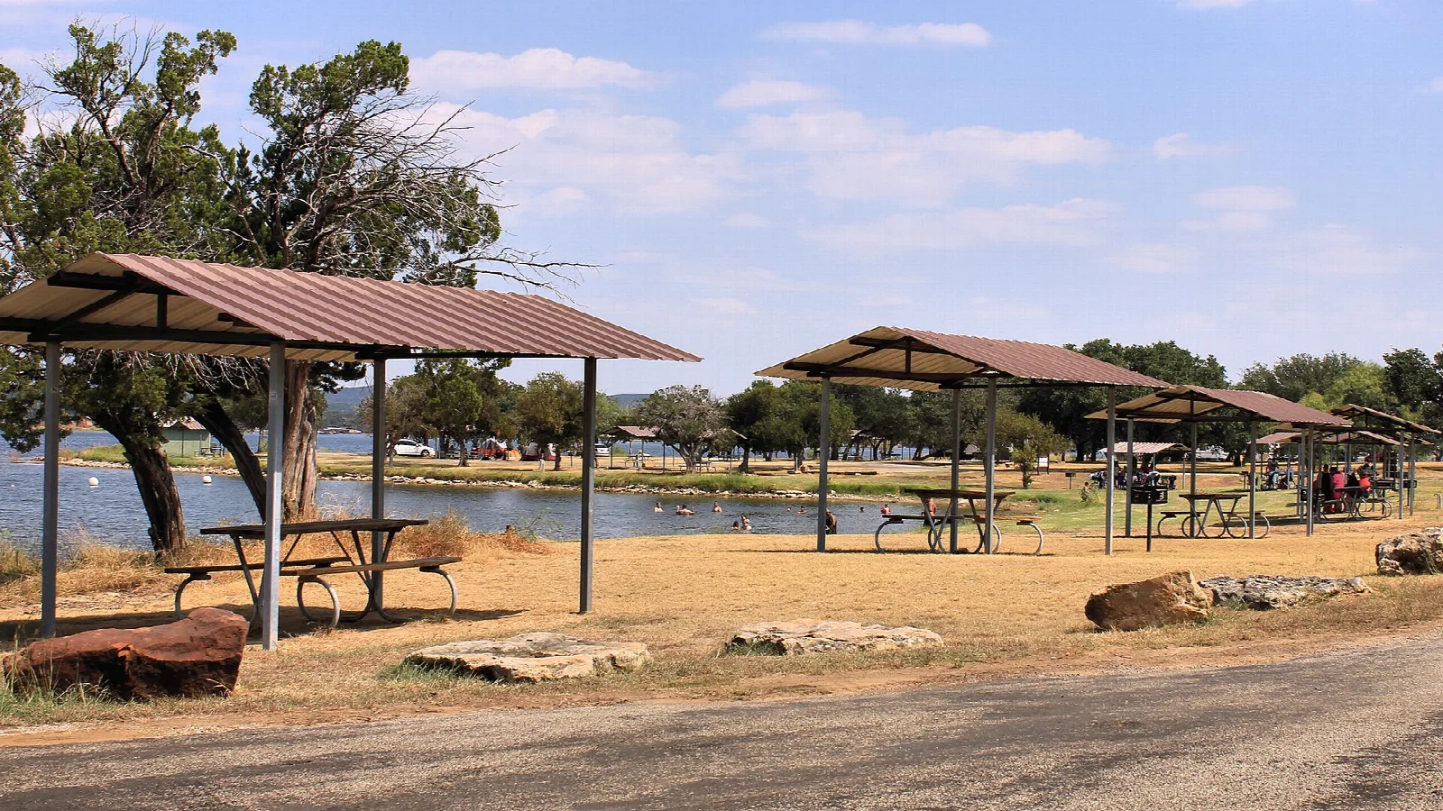 Picnic shelters with tables beside a swimming area on the lake