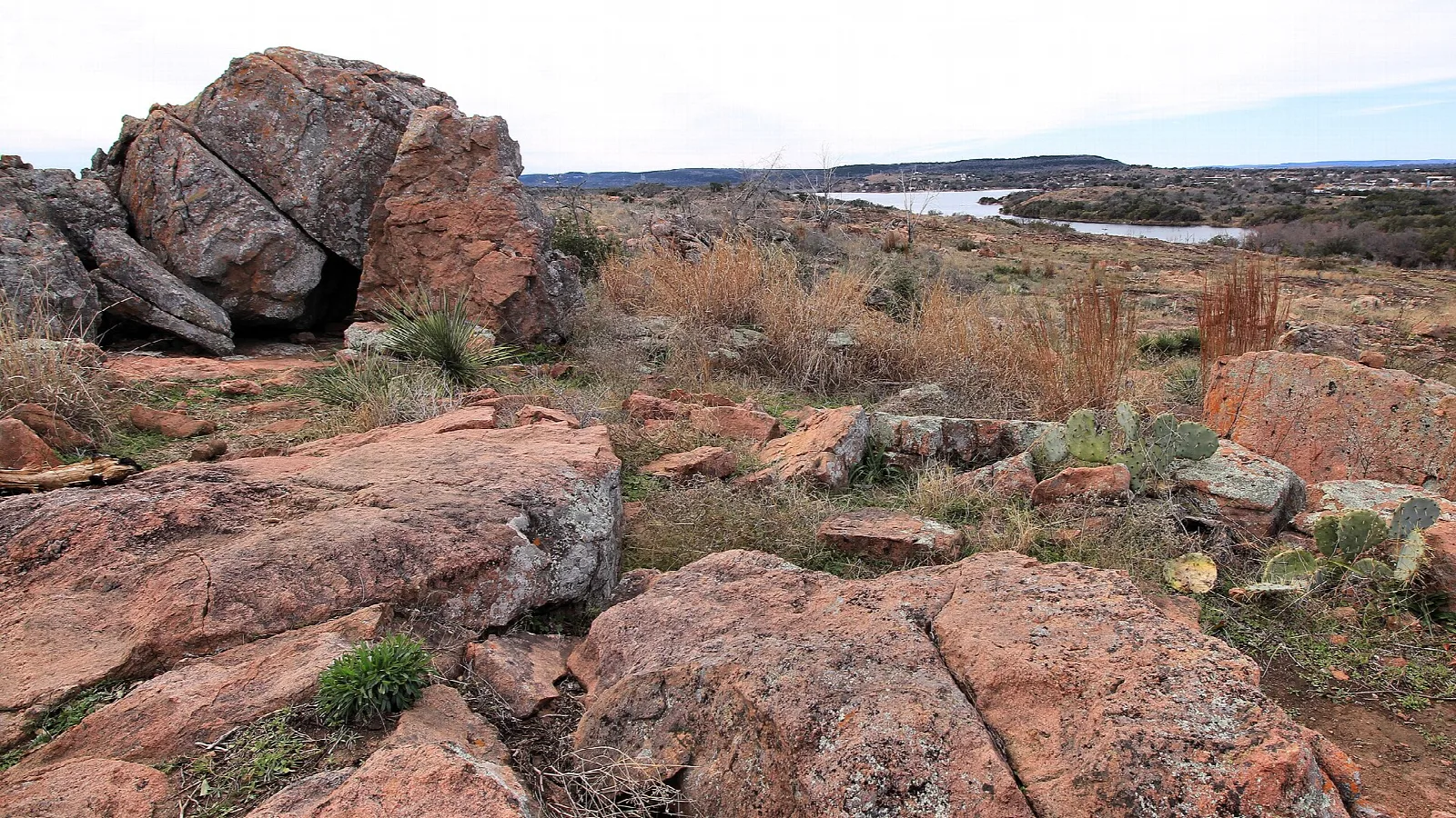Pink granite boulders on a hilltop with lake in the distance
