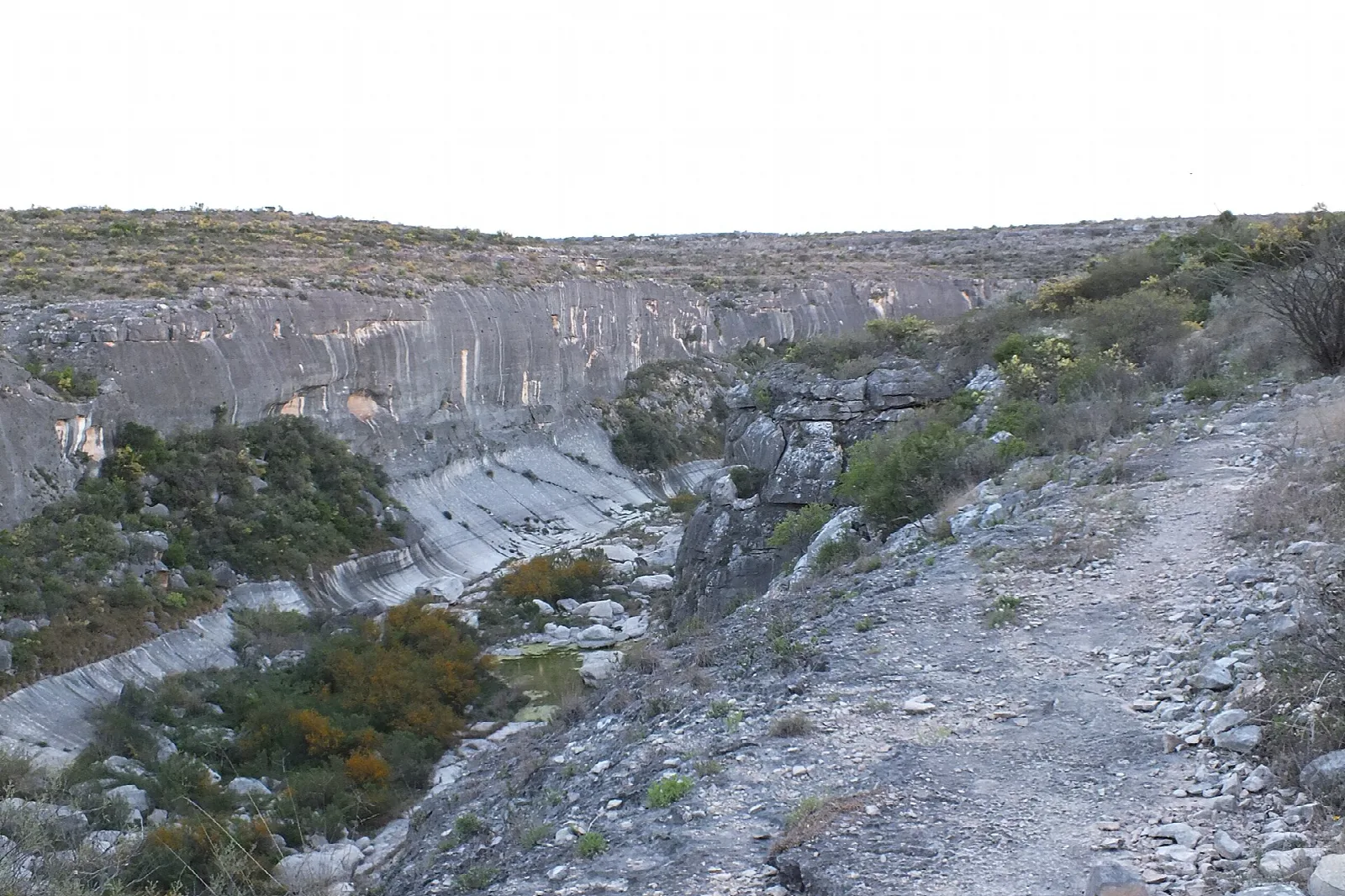 Pale rock canyon wall above a gravel trail