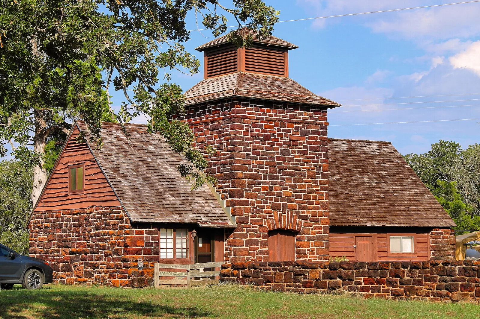 Red stone and timber cabin with a stone tower and shingled roof