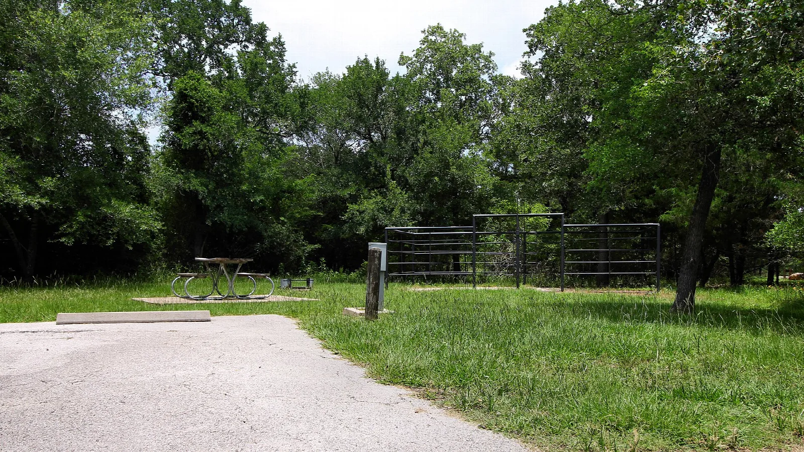 Paved pad and pipe corral fencing at an equestrian campsite in the trees