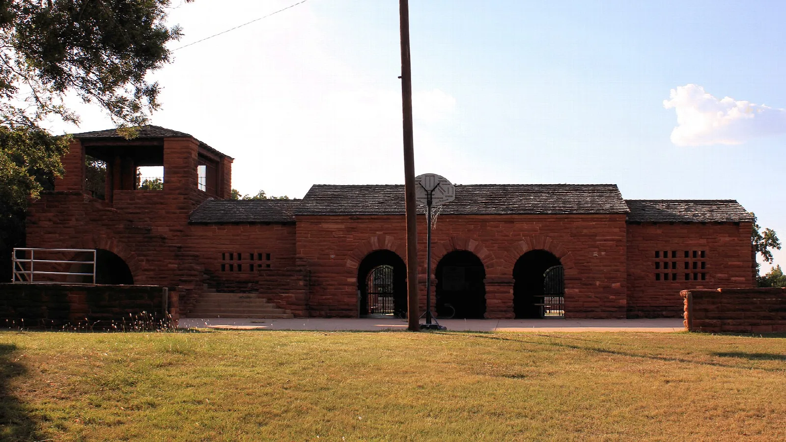 Red stone building with arched openings on a lawn