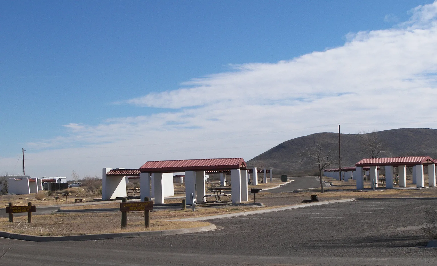Covered picnic shelters on a paved loop with a hill behind