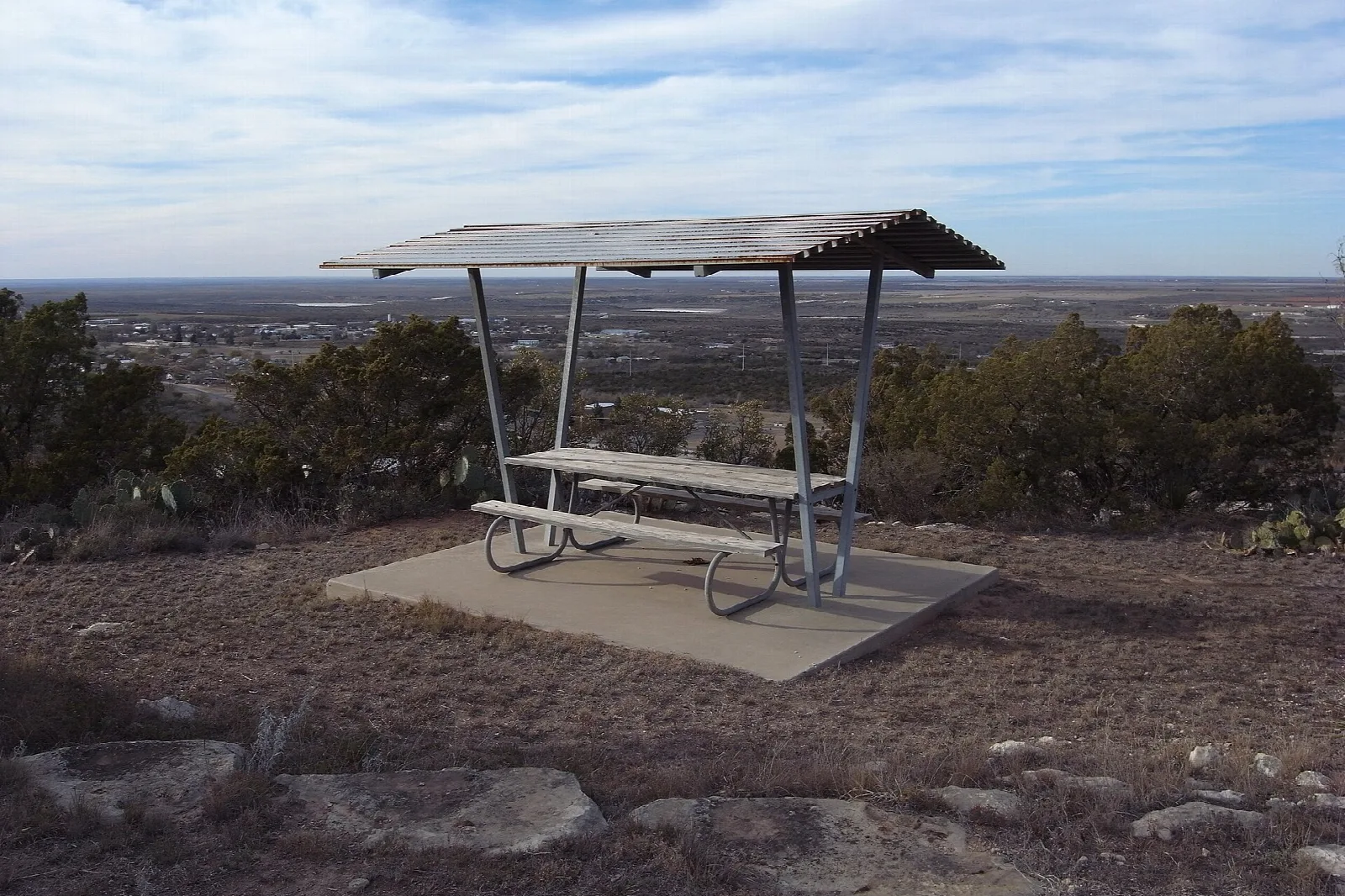 Covered picnic table on a pad with a wide view over the plain