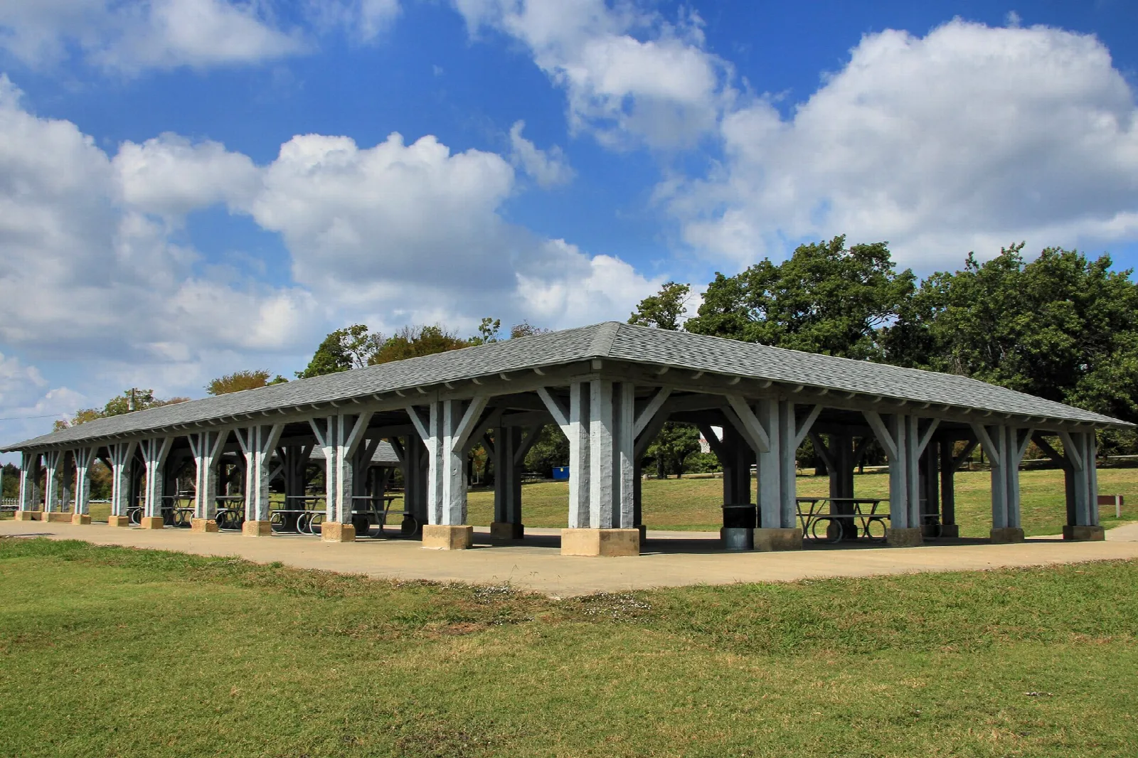 Open-sided pavilion with a gray roof and white posts on a lawn