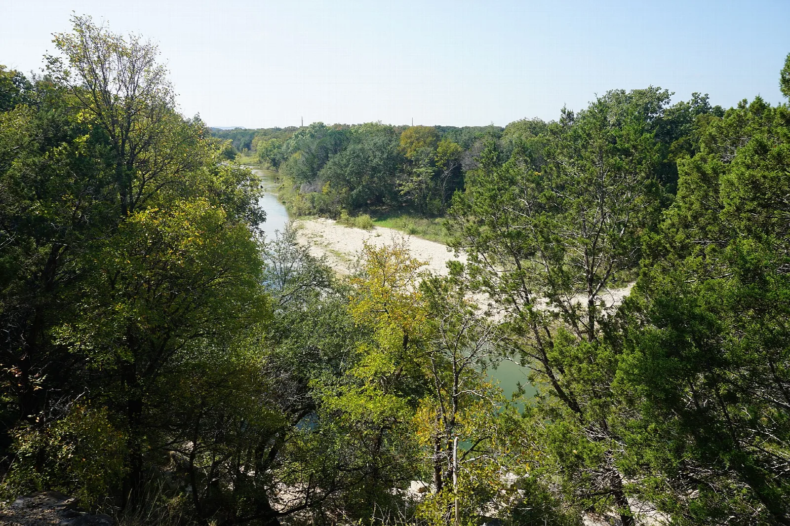 River bend with a pale gravel bar seen through green trees from above