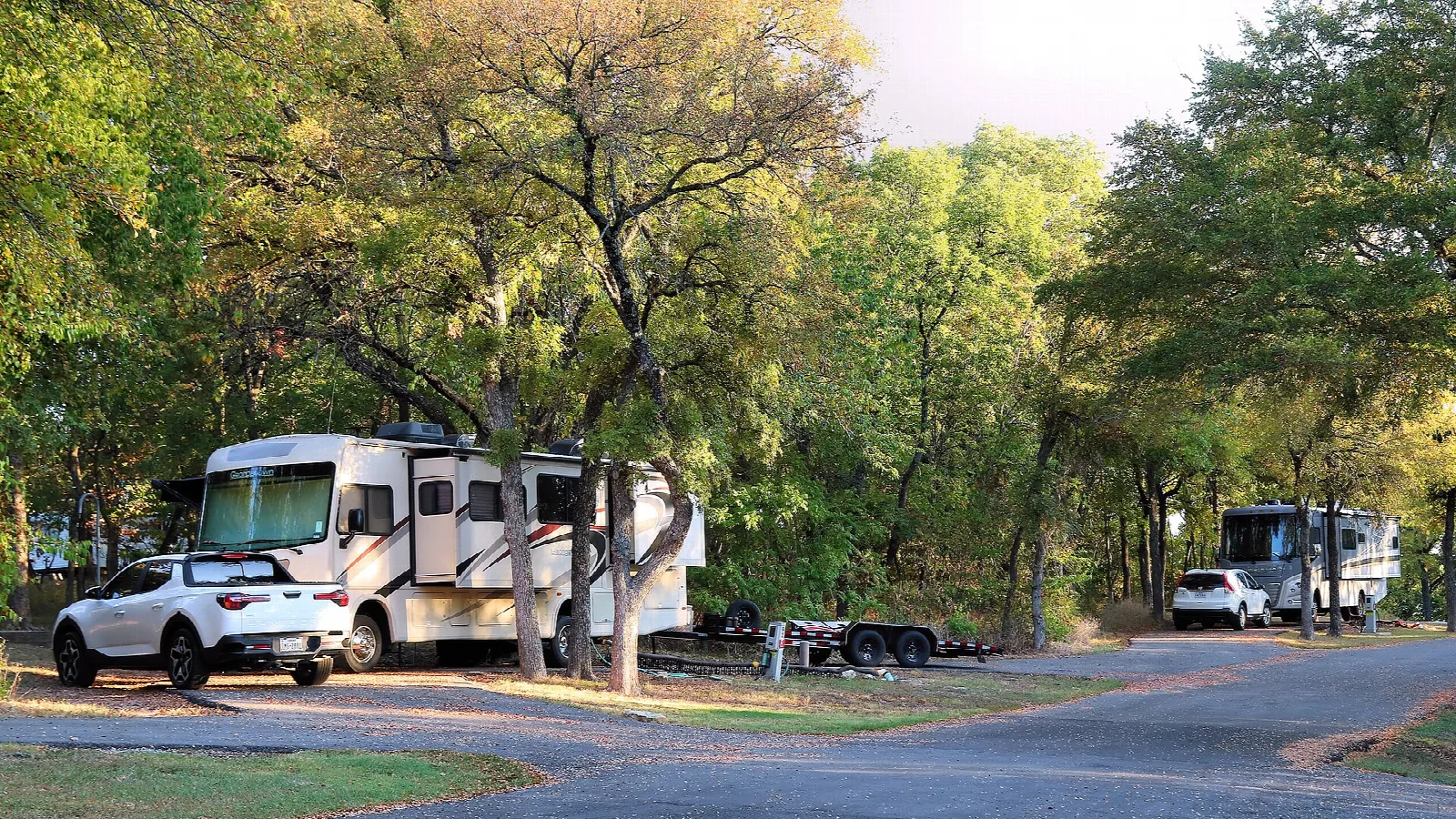 RVs parked in a shaded campground among trees