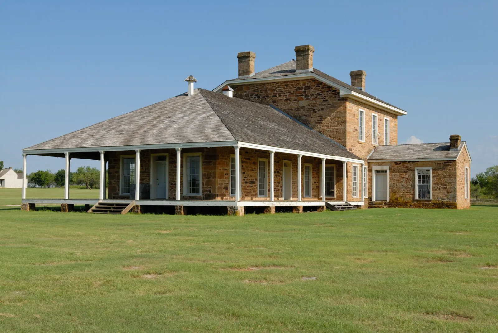 Two-story stone hospital with a wide porch on a grassy lawn