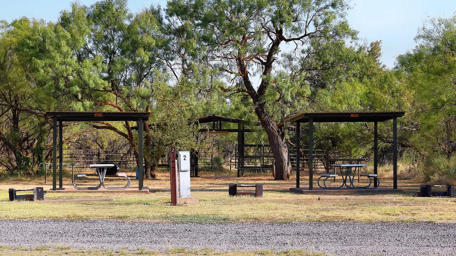 Picnic shelters among trees on a gravel lot