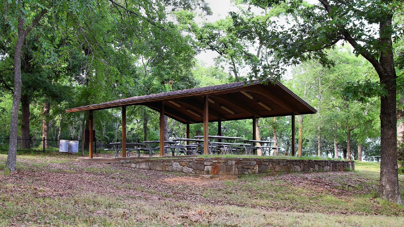 Covered picnic shelter among trees on a lawn