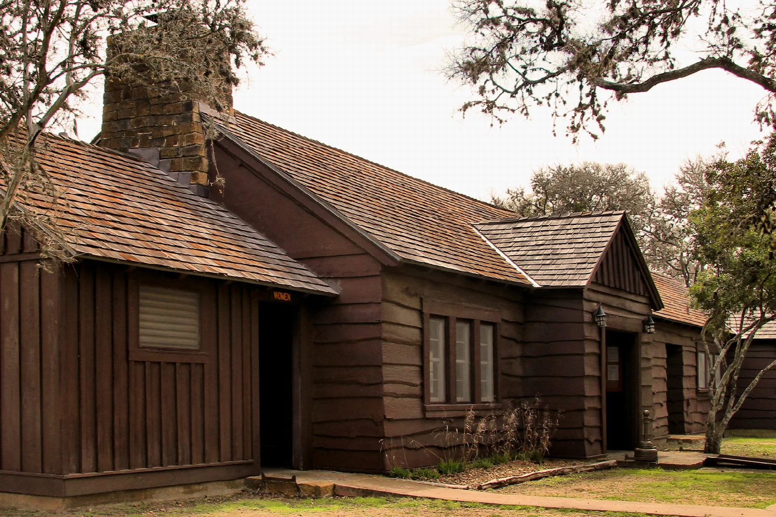 Brown wood and stone lodge building with a chimney among trees