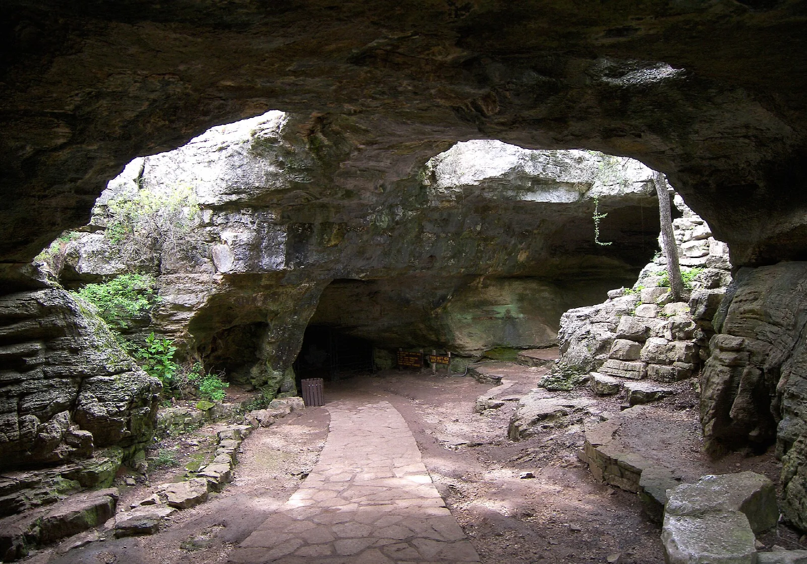Wide arched cave entrance with a paved path leading in