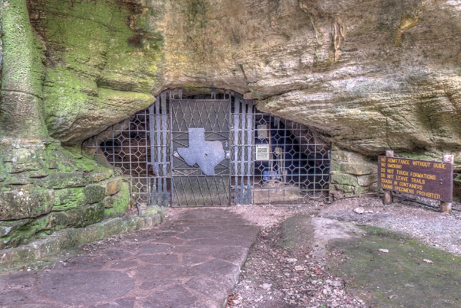 Cave mouth closed by a metal gate beneath a rock overhang