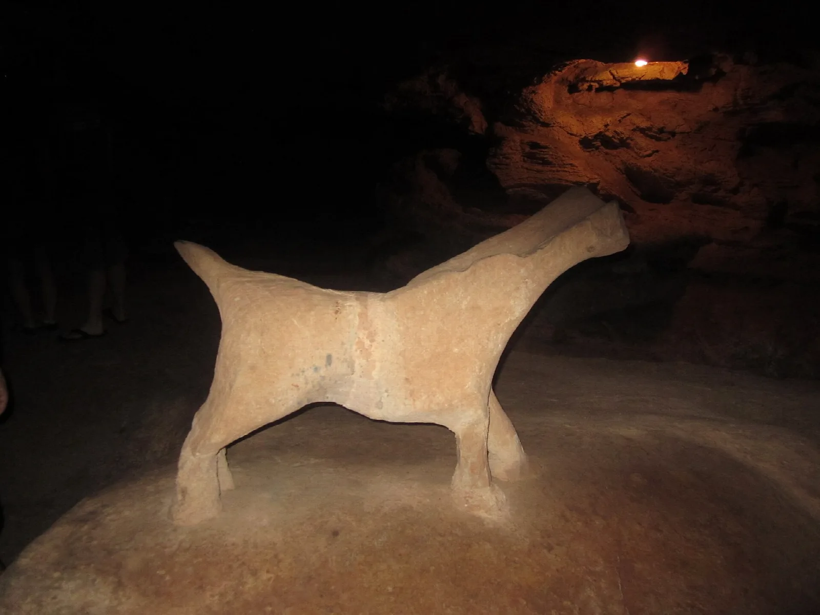 Pale cave formation shaped like an animal in a dark chamber