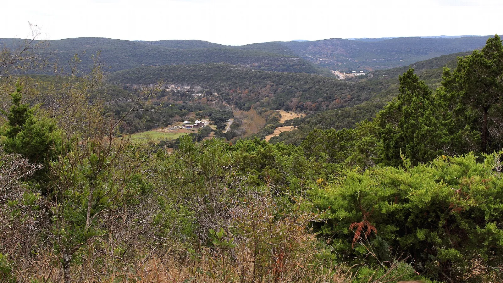Hazy view over green hills and a valley from an overlook