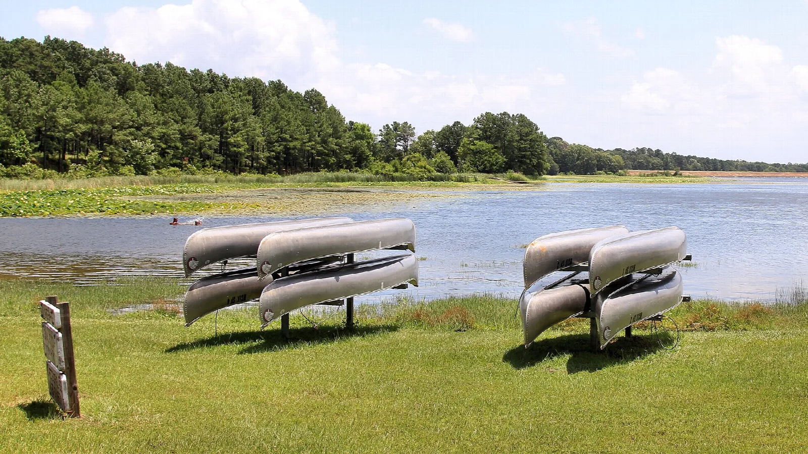 Rental canoes stacked on a grassy bank beside the lake
