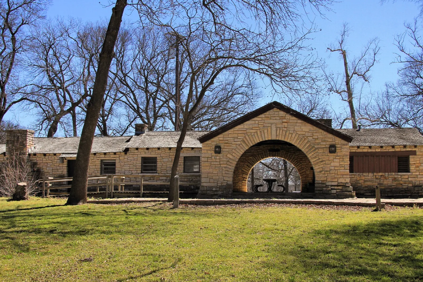 Long stone building with a central arch beside a lawn