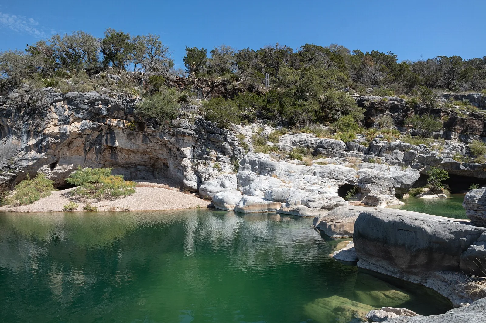 Green water pool beneath rocky cliffs