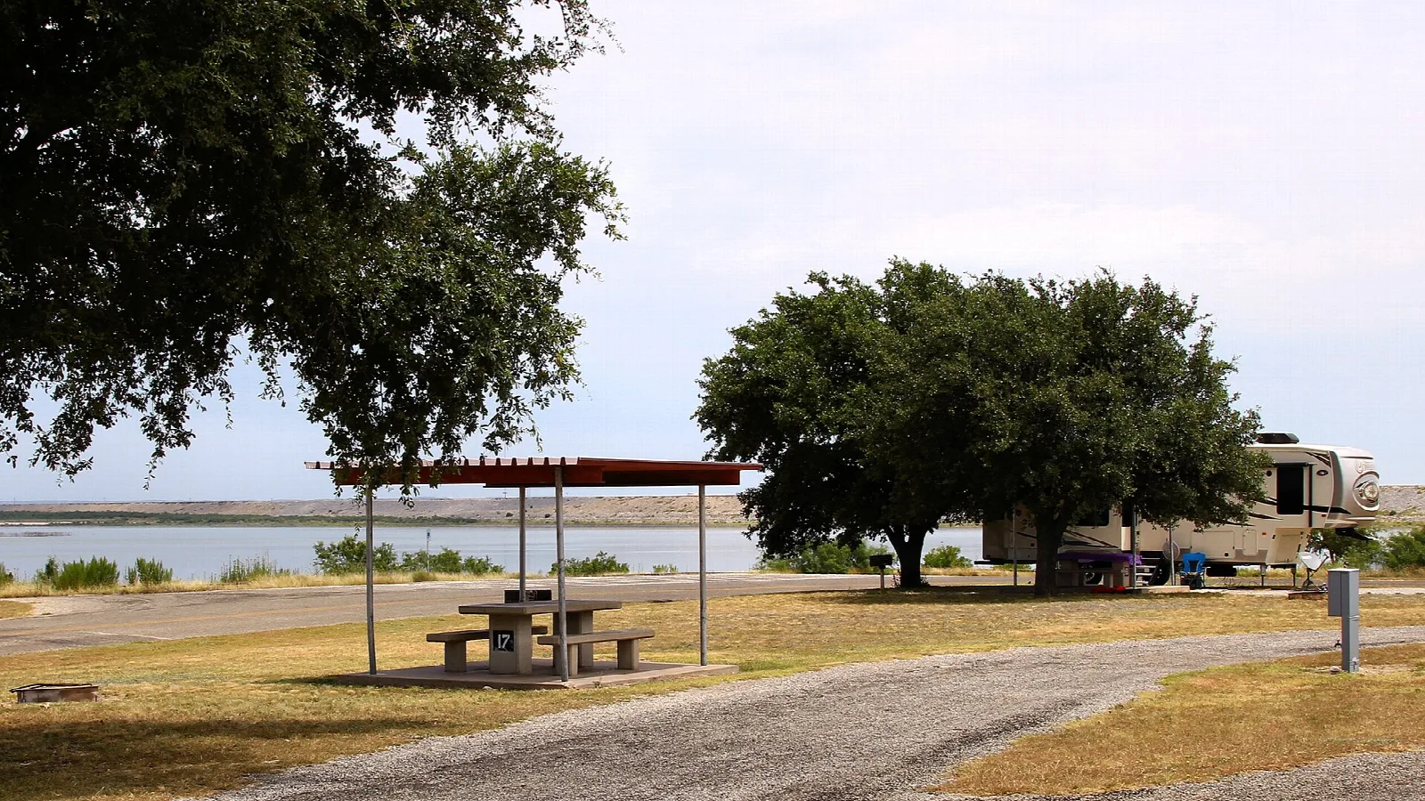 Campsite with a picnic shelter and trailer beside the lake