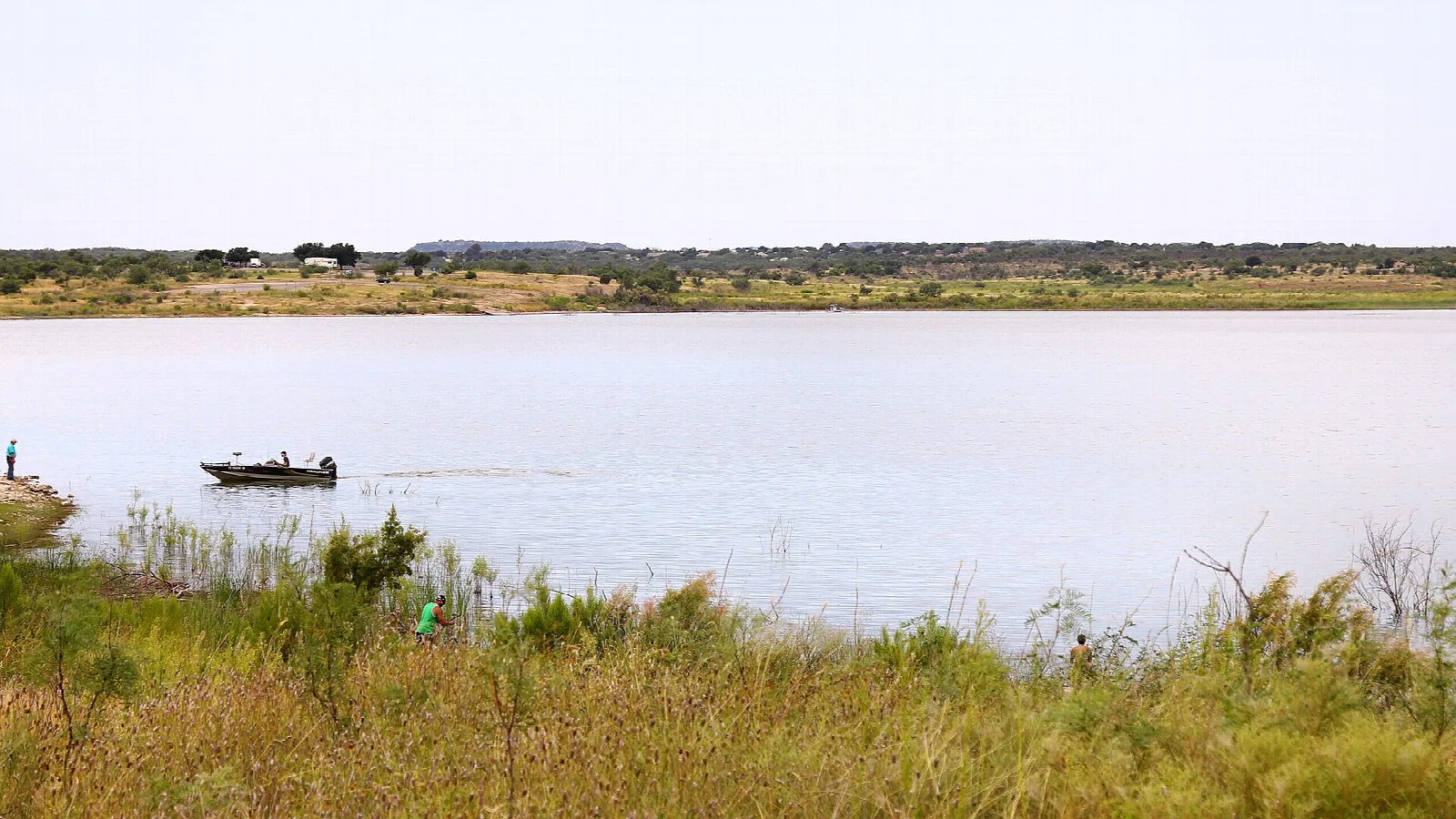 Wide reservoir with a small fishing boat and low shoreline