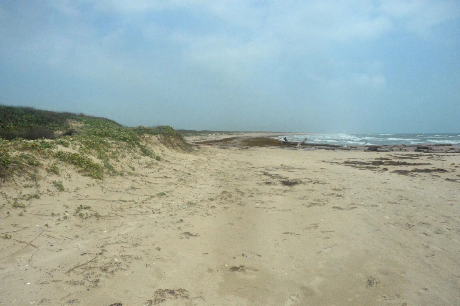 Sandy beach with grassy dunes and a hazy sky