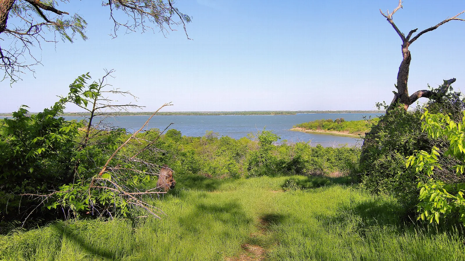 Grassy overlook trail with a wide lake in the distance