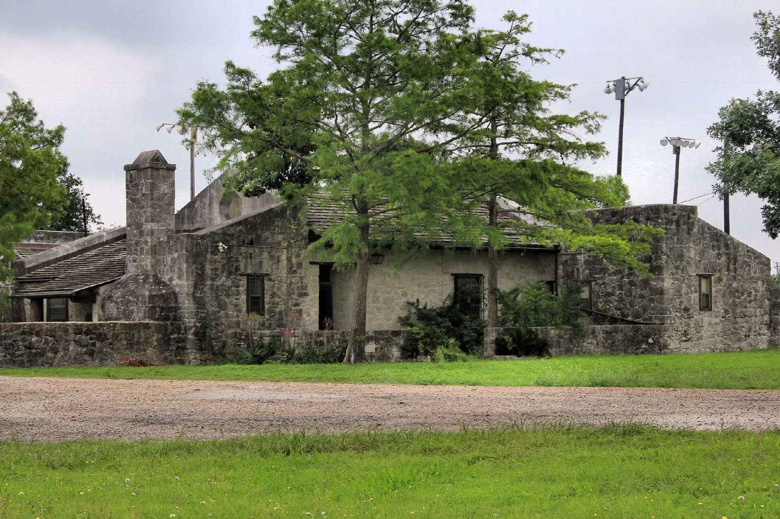 Old stone building with a tree and grass in front