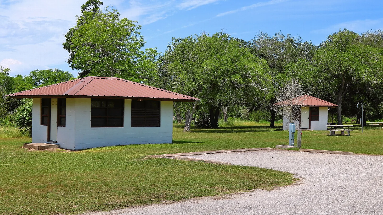 Small white screened shelters on a lawn under trees