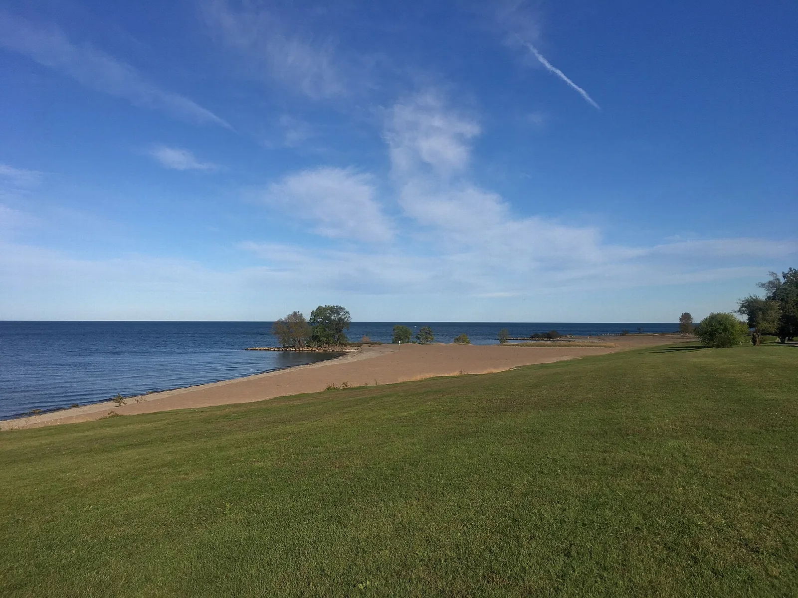 Wide lawn running to a sandy lakeshore and blue water