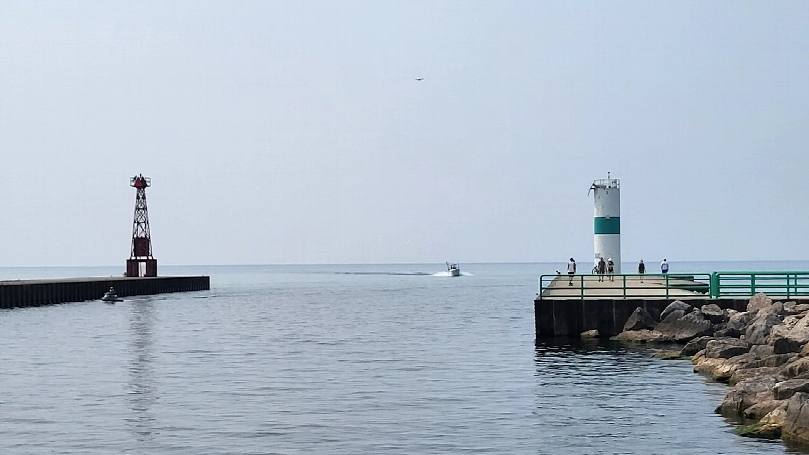 Two harbor lights on piers extending into calm Lake Michigan