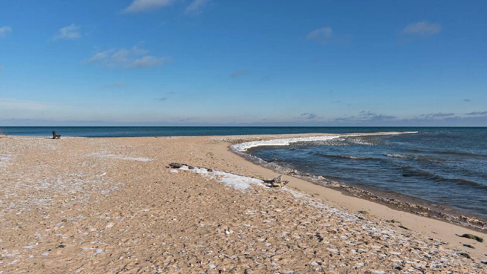 Sandy spit with a thin snow dusting reaching into Lake Huron