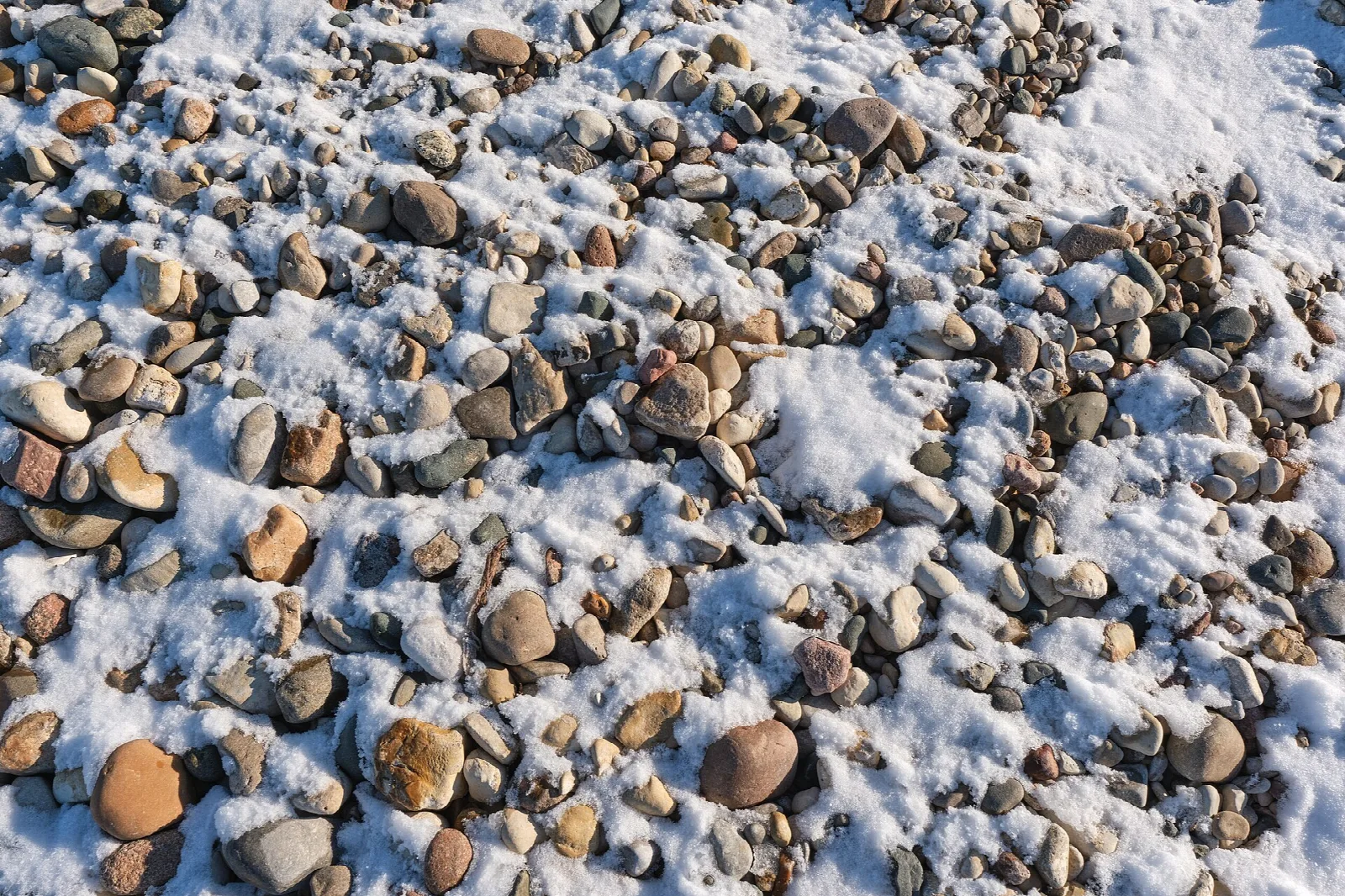Close view of rounded beach pebbles dusted with snow