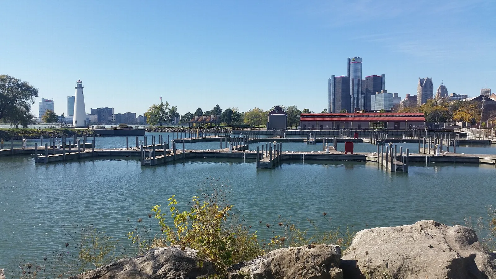 Boat harbor with floating docks, rocks in front and the Detroit skyline behind