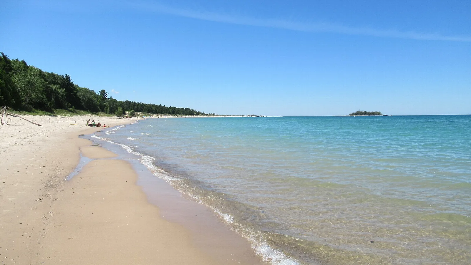 Sandy Lake Michigan beach with clear blue-green water and a small island offshore